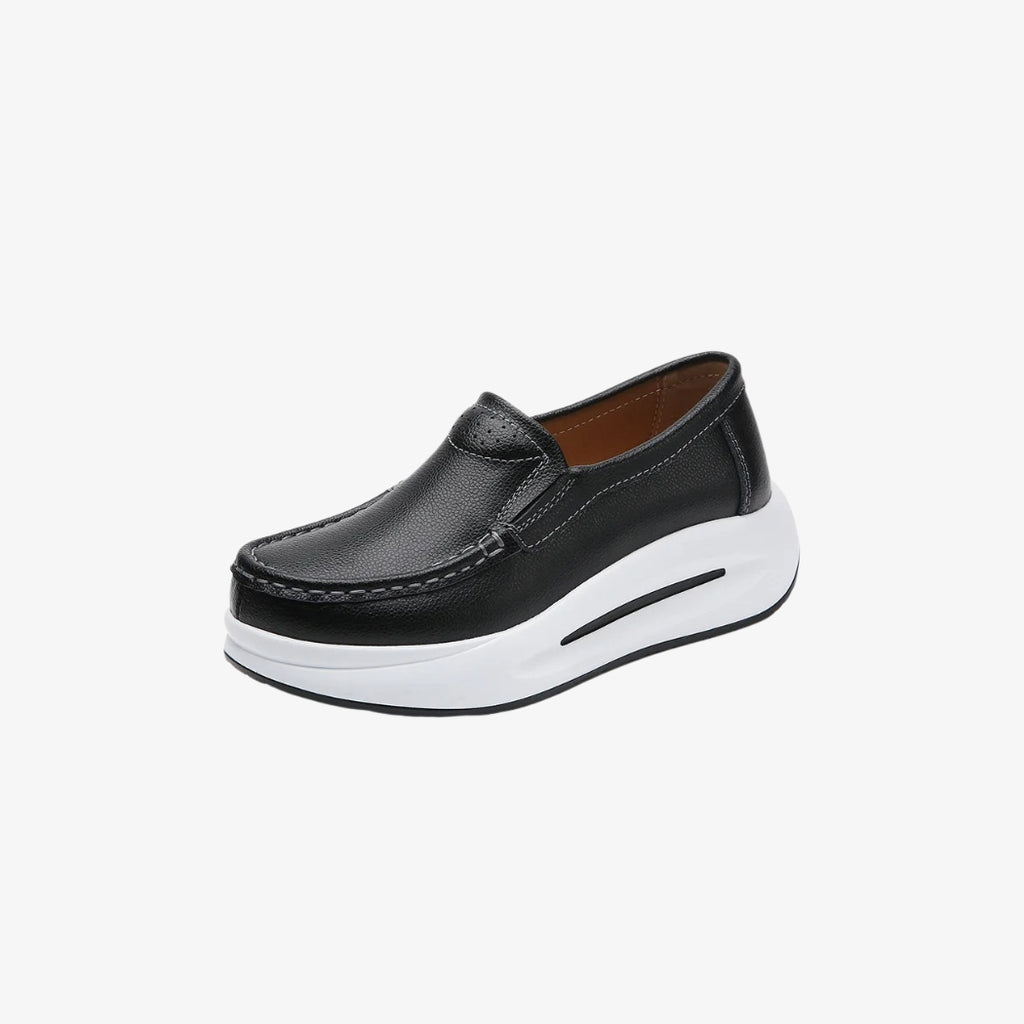 Mocassins pour femme en cuir noir, dotés d'une semelle épaisse blanche pour un style moderne et confortable. Leur design minimaliste inclut des coutures apparentes et un ajustement facile, parfaits pour un look à la fois élégant et décontracté.