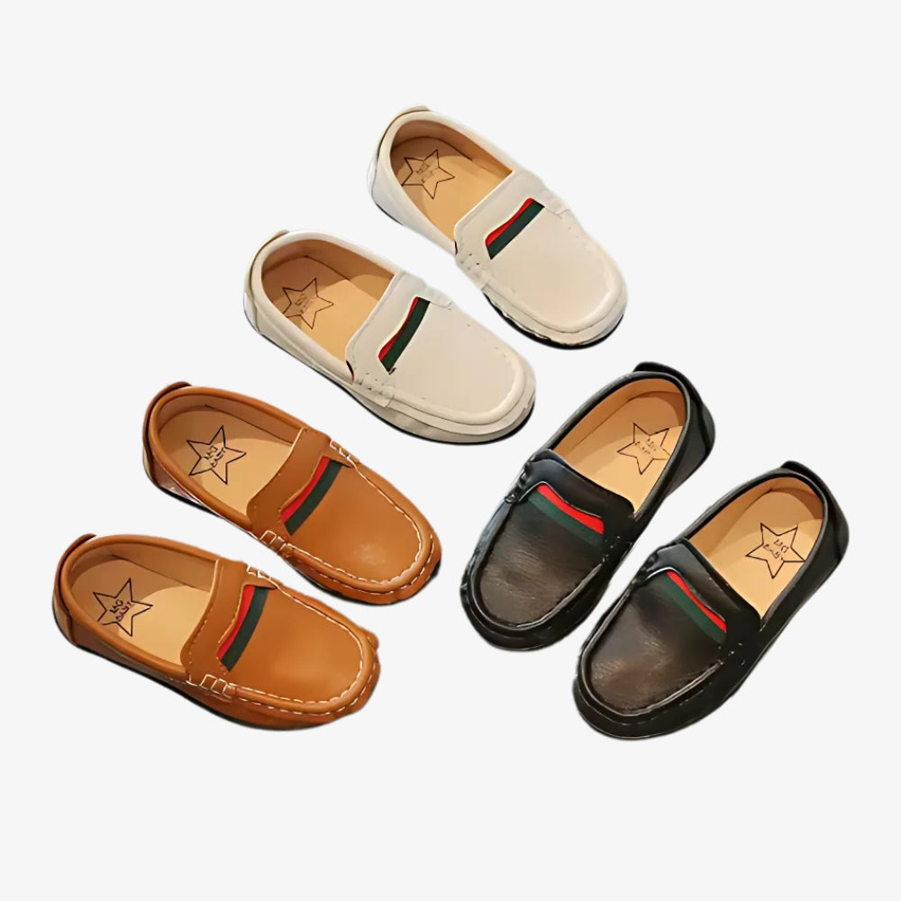 Mocassins souples en cuir avec un design rouge et vert pour garçons sur fond gris clair.