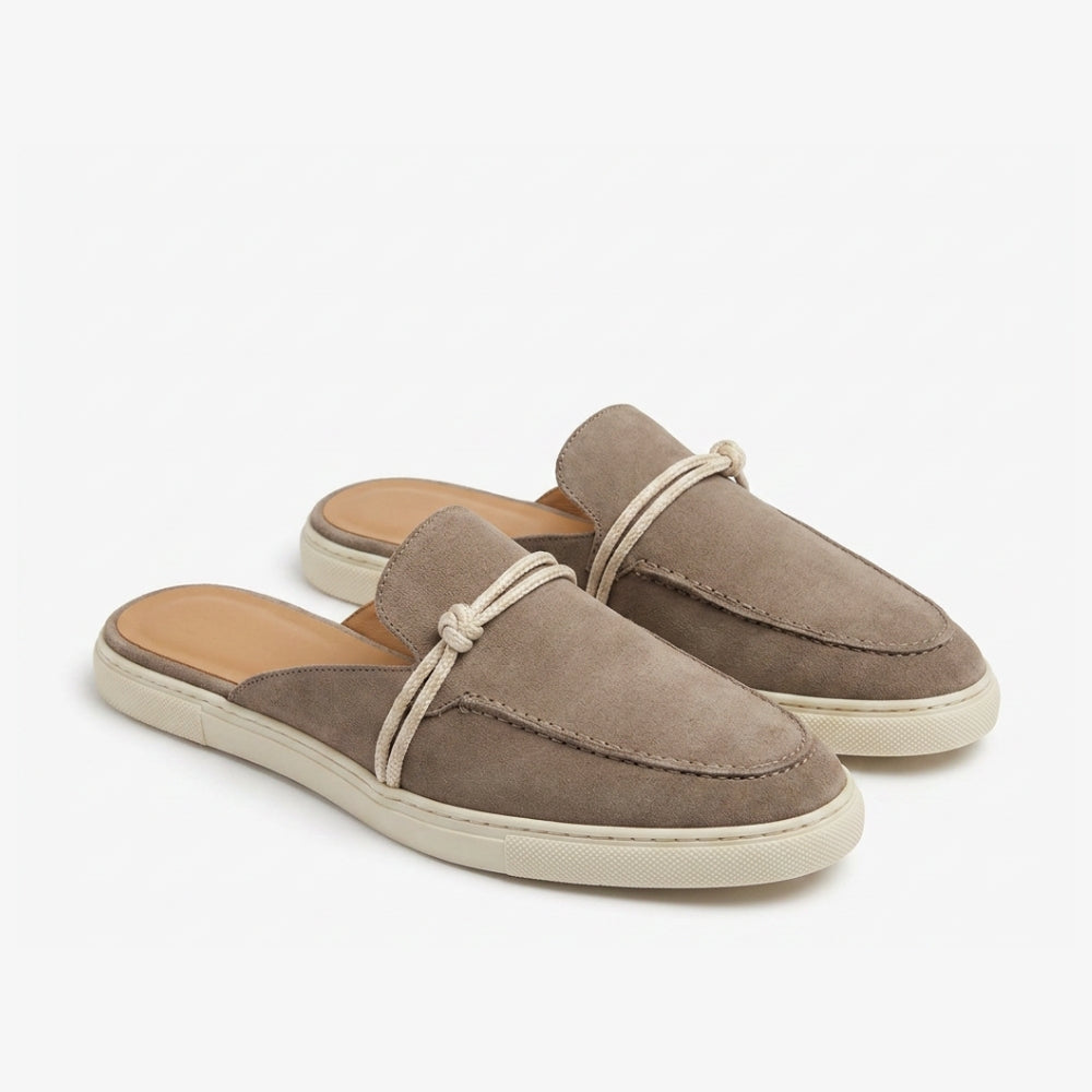 Mocassin mule en cuir suédé véritable, coloris marron taupe avec une semelle et une bride beige, sur fond gris