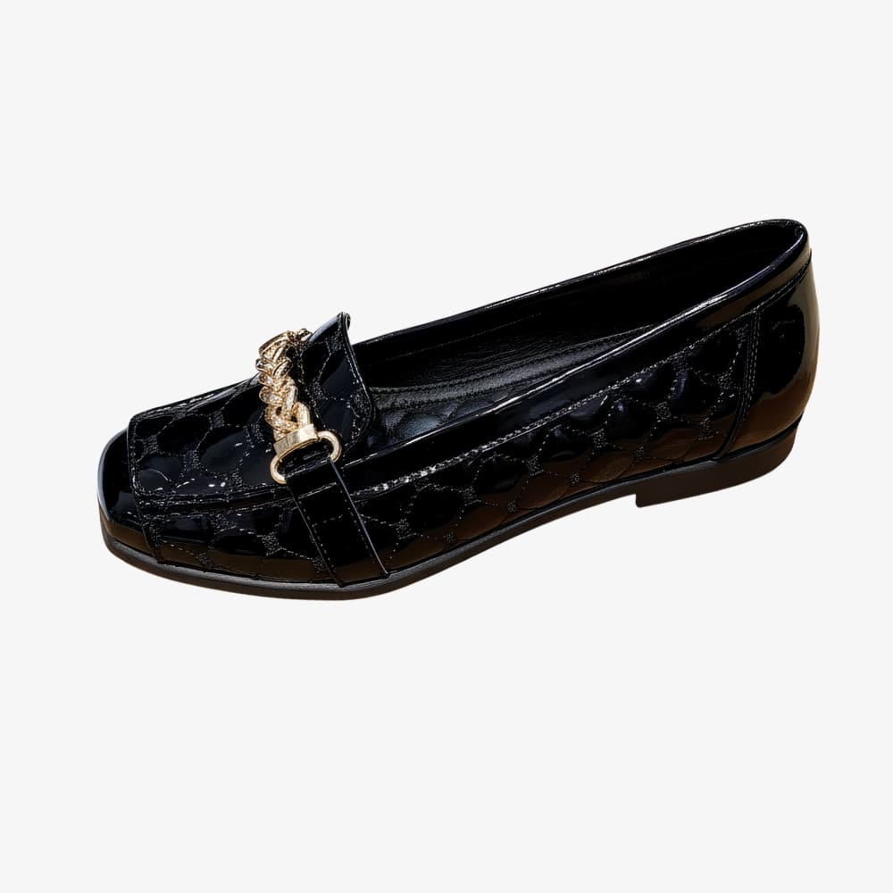 Mocassins en cuir synthétique verni pour femme avec chaine dorée décorative avec petit talon sur fond blanc.