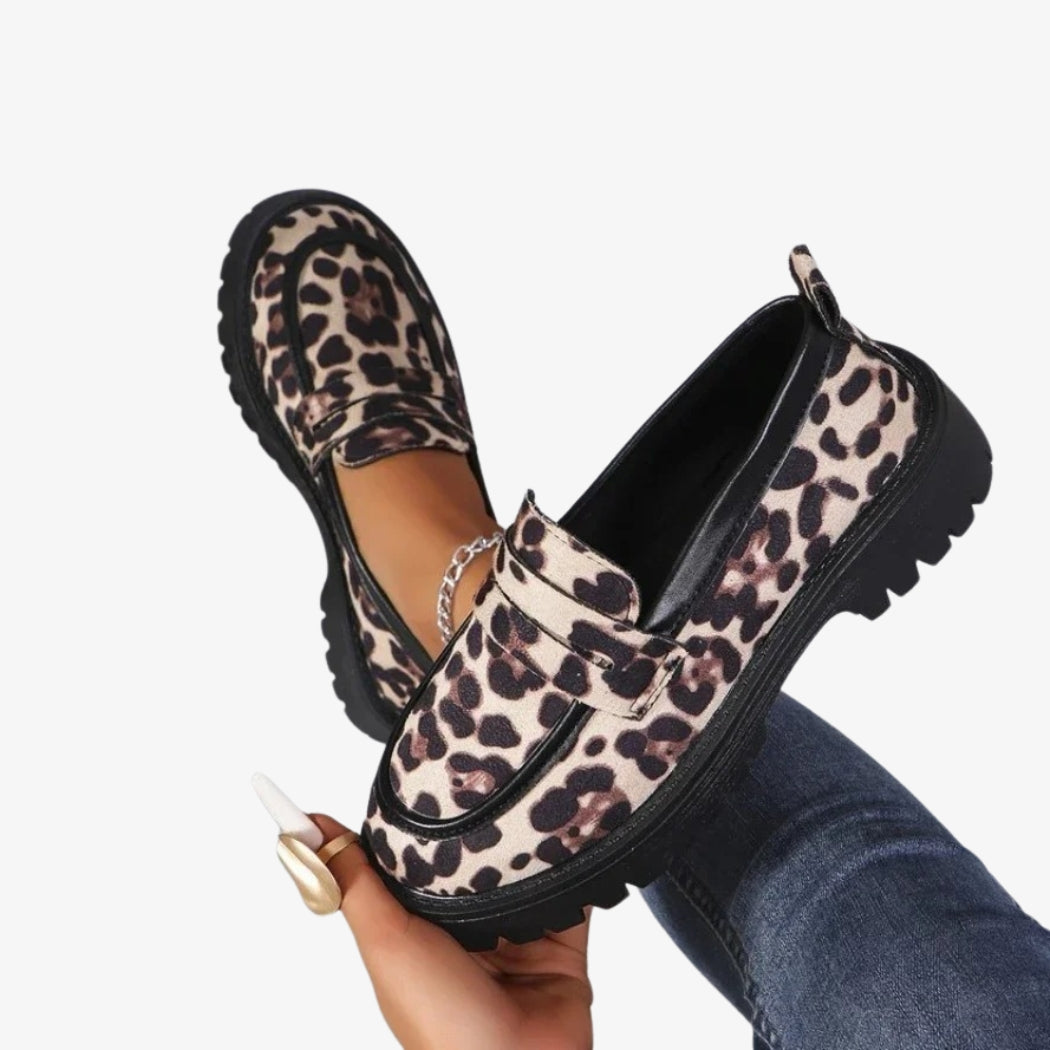 Mocassins pour femmes avec un imprimé léopard audacieux, parfaits pour un look tendance. Ces chaussures sont dotées de semelles épaisses et crantées noires, offrant à la fois style et adhérence. Le design inclut une mariée décorative sur le dessus pour une finition élégante.