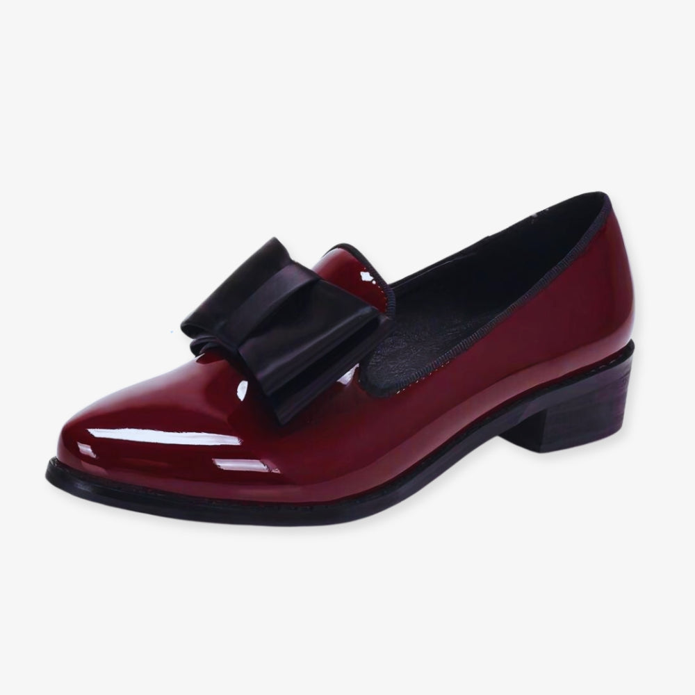 paire de mocassins grenat en cuir synthétique verni, portés, sur un sol gris