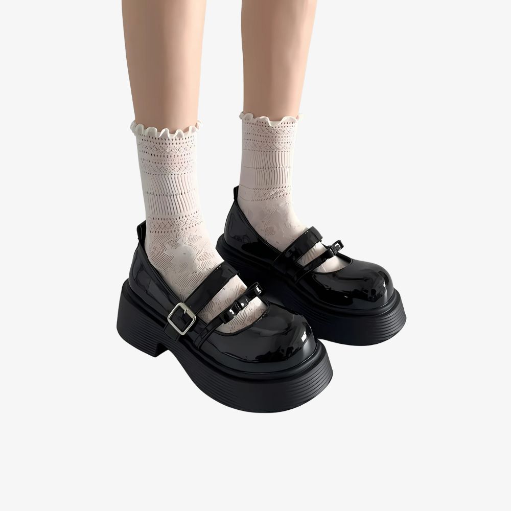Jambes de femme avec des mocassins noirs à plateforme avec deux brides, portant des chaussettes hautes blanches.