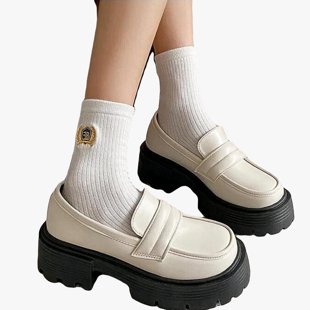 on voit les pieds d'une femme avec des mocassins compensés en cuir synthétique blanc
