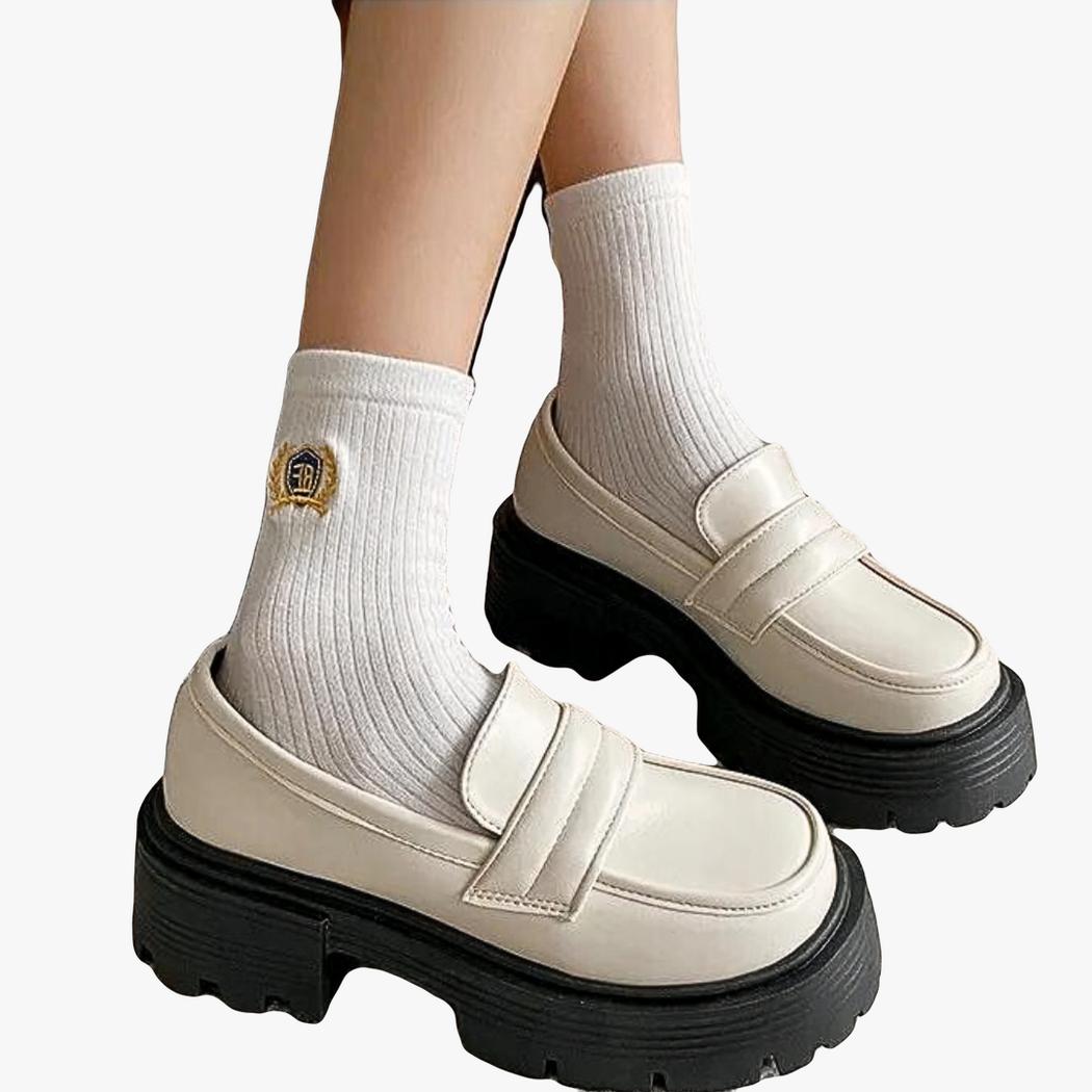 on voit les pieds d'une femme avec des mocassins compensés en cuir synthétique blanc
