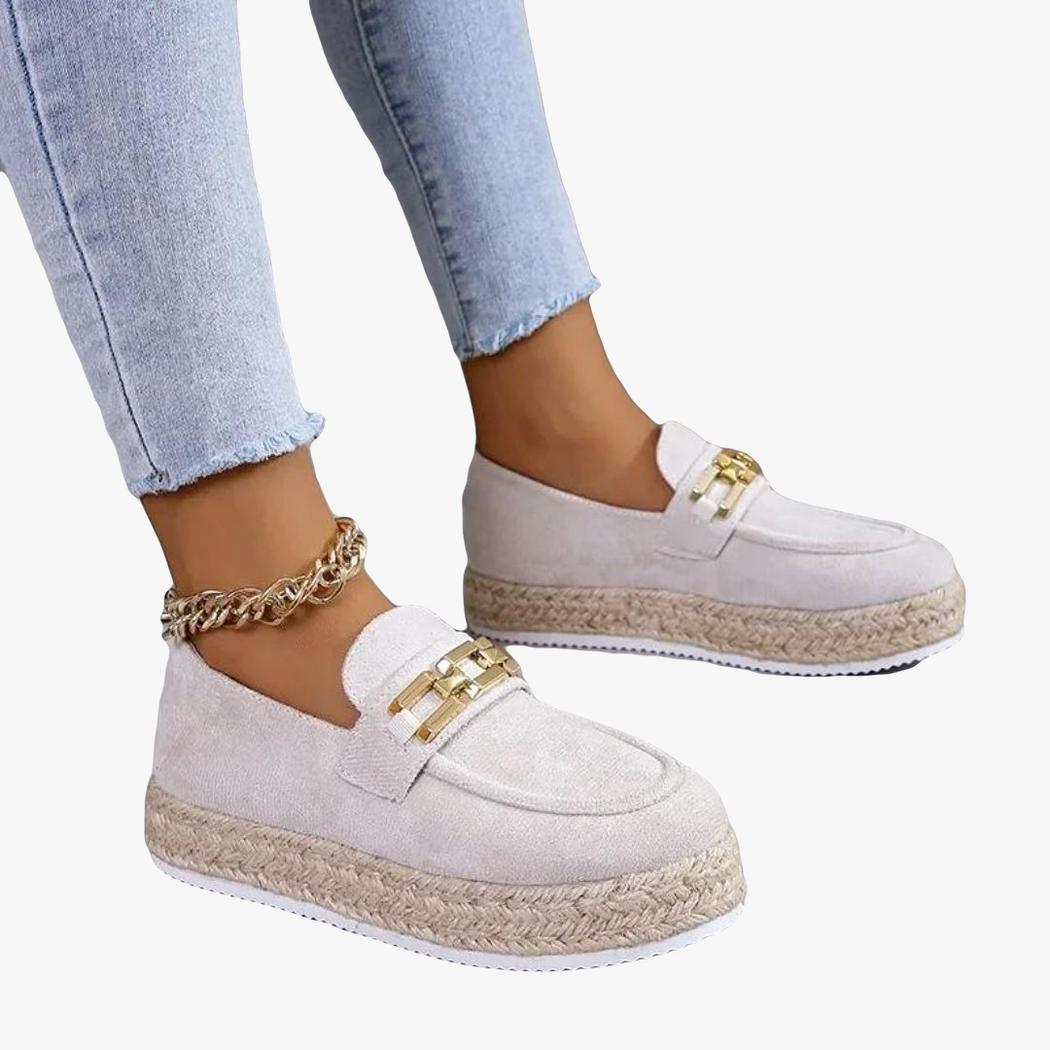 on voit les pieds d'une femme en jean qui porte des mocassins compensés en daim synthétique de couleur beige
