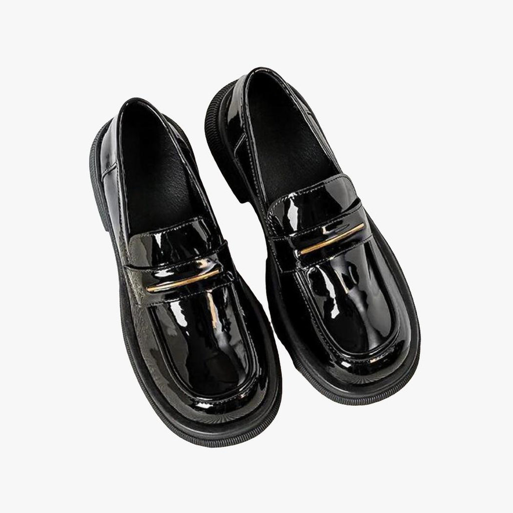 on voit sur un fond clair une paire de mocassins noirs vernis en cuir synthétique pour femme