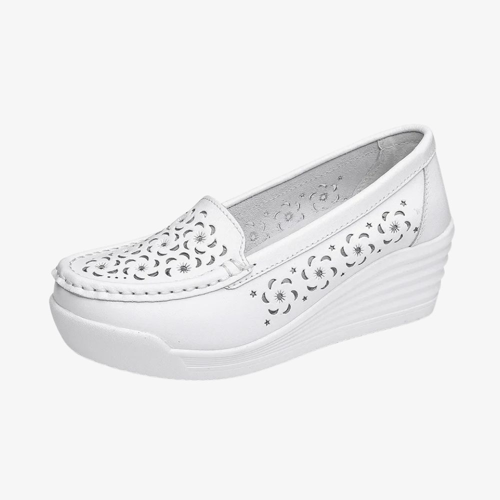 Un mocassin blanc de profil, avec une semelle compensée et des trous sur le devant et les côtés.