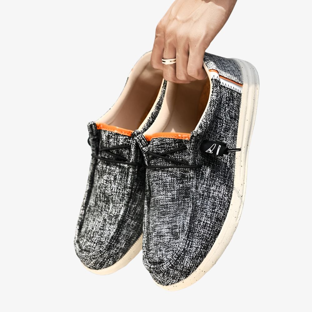 Paire de mocassins pour homme en toile de couleur grise avec des petites taches noires et une semelle blanche.