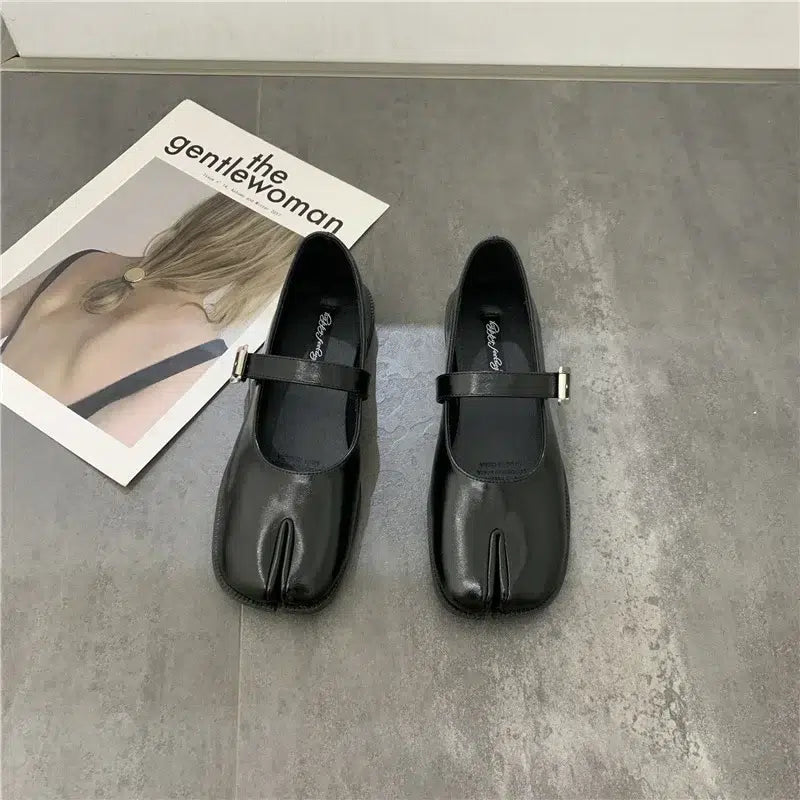Paire de ballerines Mary Jane cuir fendu noir pour femmes - Style Tabi sur un sol gris devant un magazine