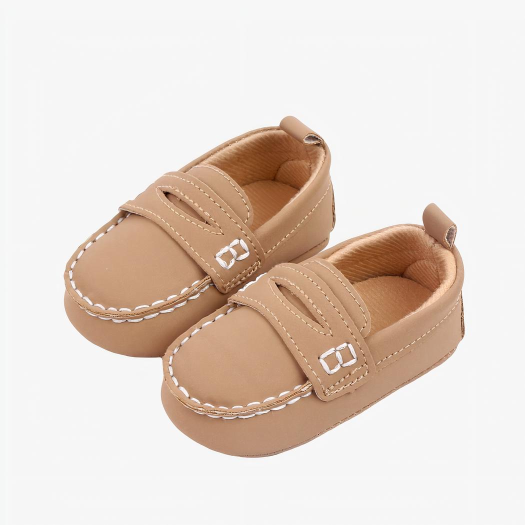 mocassin pour bébé marron en faux cuir avec les couture apparente blanches poser sur un fond blanc