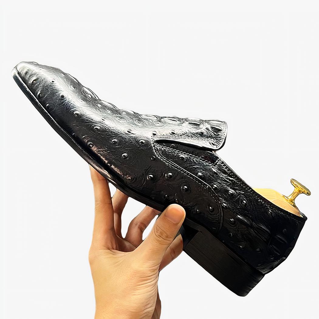 Une personne tient en main un mocassin noire façon crocodile avec une chausse pied à l'intérieur