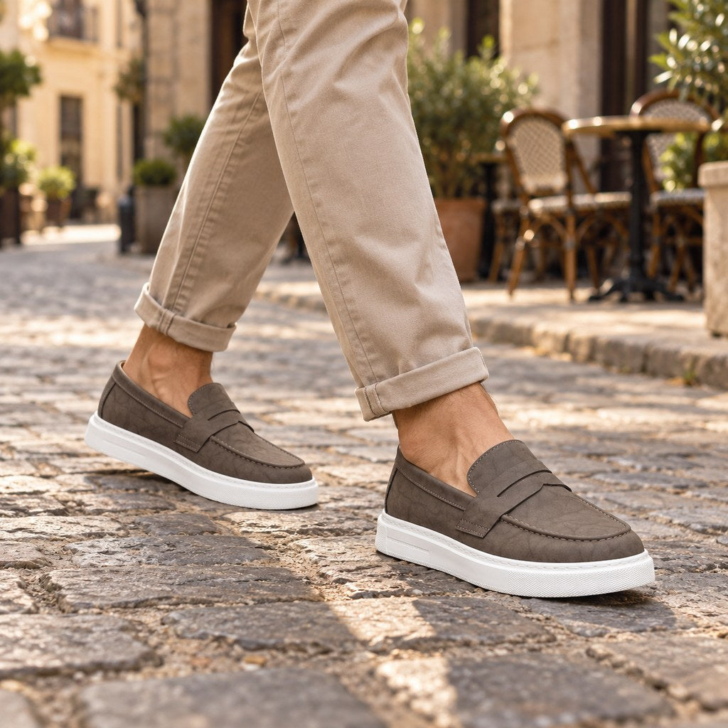 Homme en chino beige portant le mocassin à semelle blanche sur une rue pavée