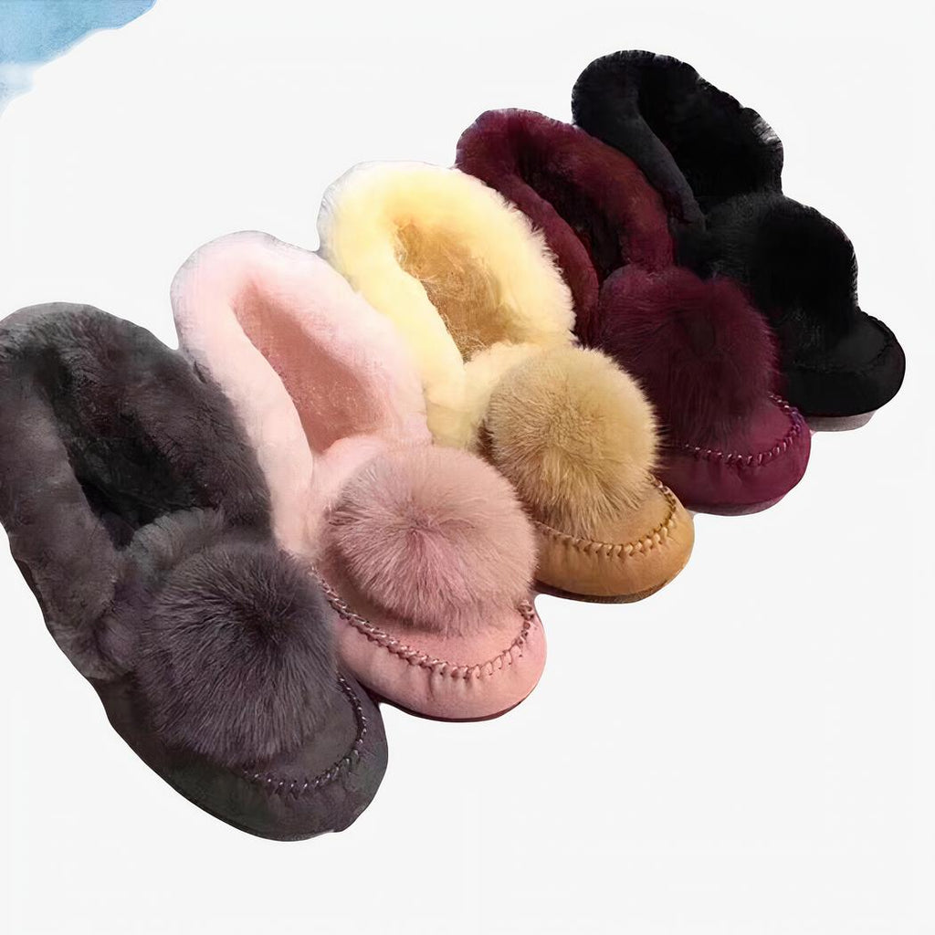 Mocassins indien d'hiver, en daim fourré avec un pompons dessus, de différentes couleurs, posés sur un canapé
