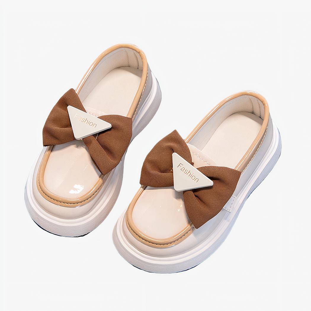 mocassin en faux cuir blanc avec un noeud marron dessus poser sur un fond gris