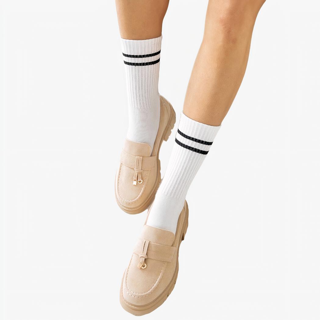 Jambes de femme portant des chaussettes hautes blanches et des mocassins à gland beige