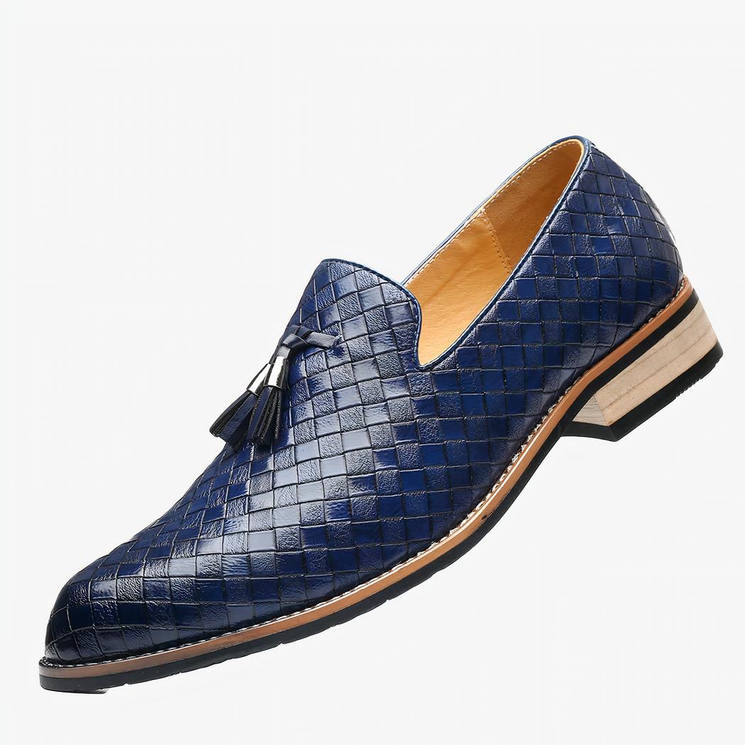 Un mocassin en cuir bleu tressé avec semelle clair et glands décoratifs sur un fond blanc.