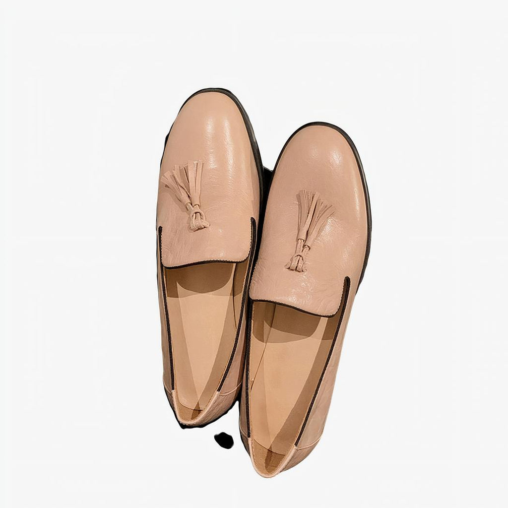 Paire de mocassins en cuir rose posée sur un élément noir