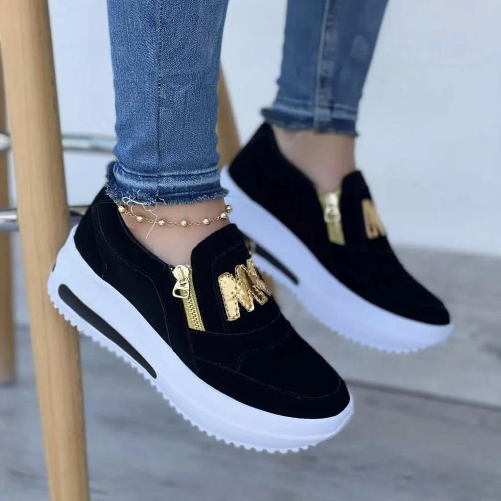 Paire de mocassins noirs portés par une femme avec un jean, dont on ne voit que les pieds