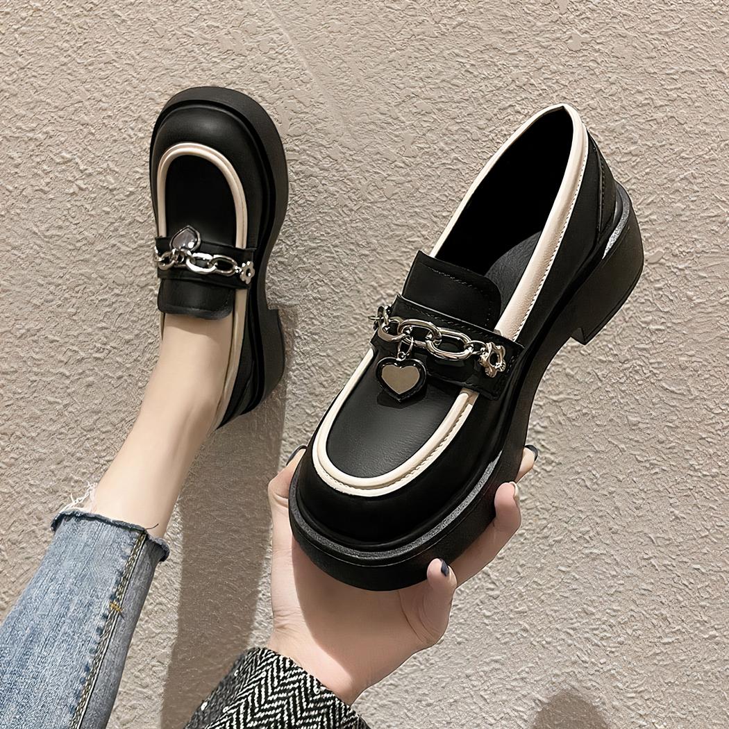 Photo d'une paire de mocassins à plateforme noire portée par une femme en jean sur un sol beige