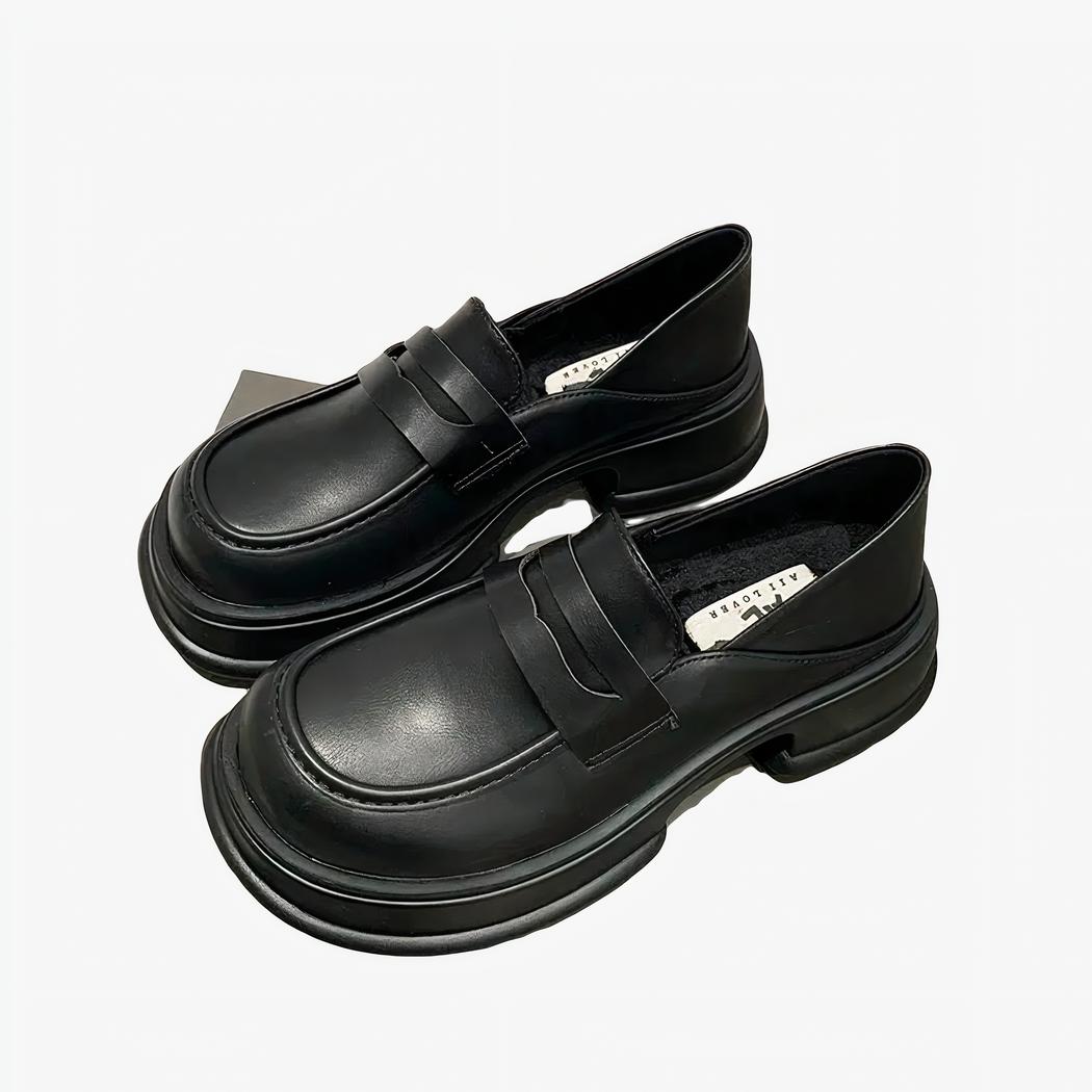 Deux mocassins noirs posés sur une boite