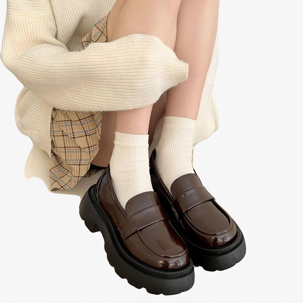 Mocassins à plateforme en cuir du style punk pour femmes avec un fond une femme qui est assise dans une chaise avec les mocassins