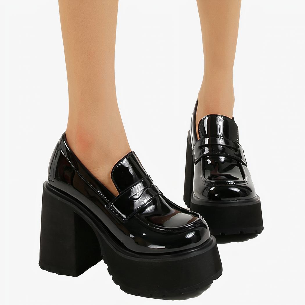 deux mocassins pour femmes vernis en noir brillant avec une grosse semanelle sur fond blanc