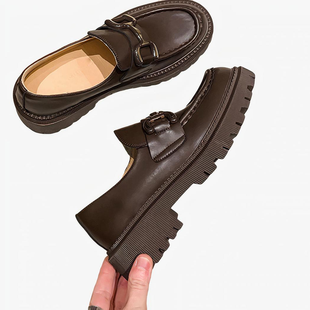 Deux mocassins sur un sol beige noir à gland, un est couchée