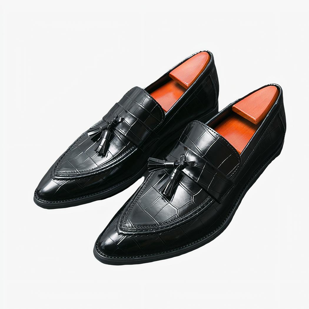 Mocassins noirs à gland aspect peau de crocodile posé sur un sol noir