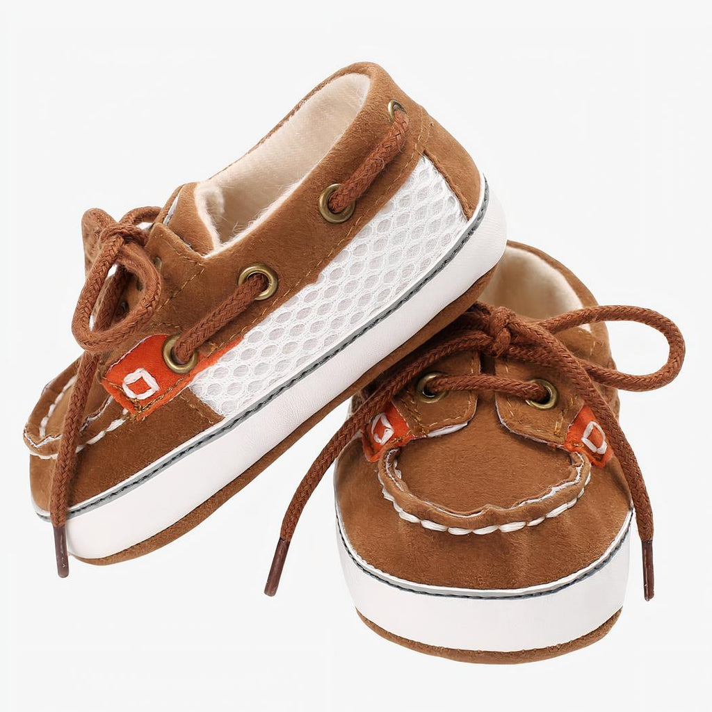 Mocassins bicolores style bateau marron et beige à lacets, sur fond blanc