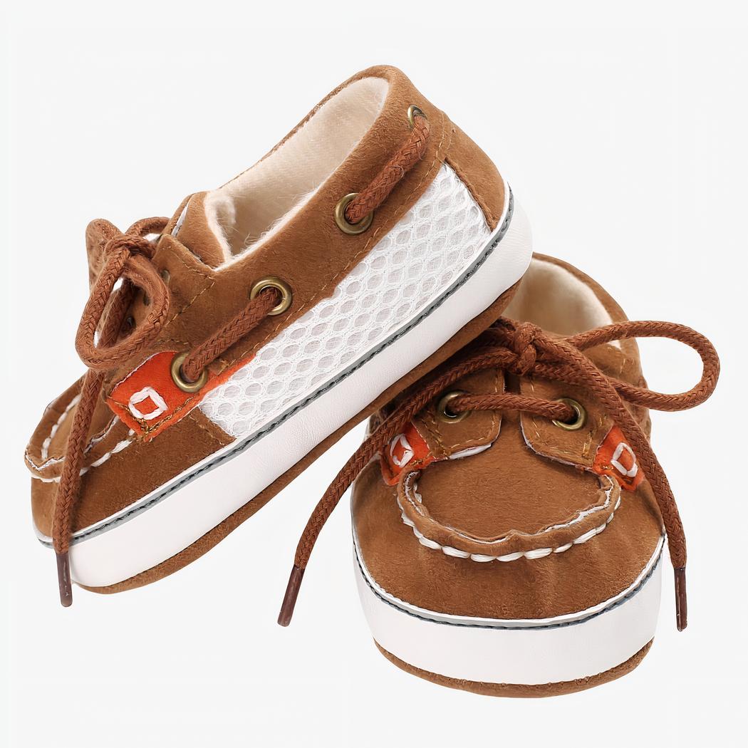 Mocassins bicolores style bateau marron et beige à lacets, sur fond blanc
