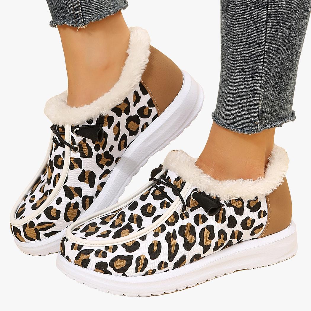 Porté avec un jean bleu, une paire de mocassins d'hiver blancs avec imprimé léopard et bordure en fourrure beige apparente. La semelle est blanche et épaisse et il y a des lacets noirs décoratifs sur le dessus du chaussant