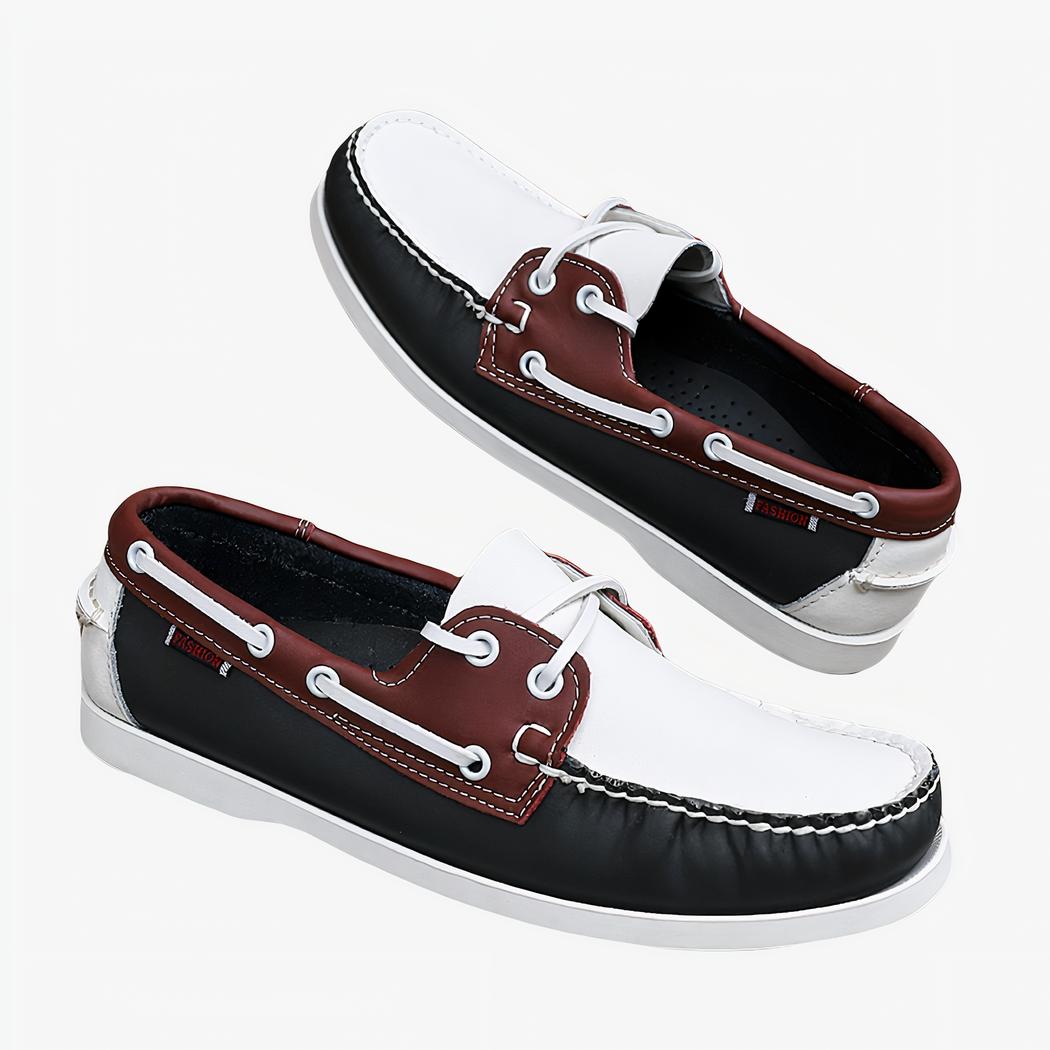 Photo d'une paire de mocassins blanc, rouge et noir posés sur un mur de briques et un sol gris