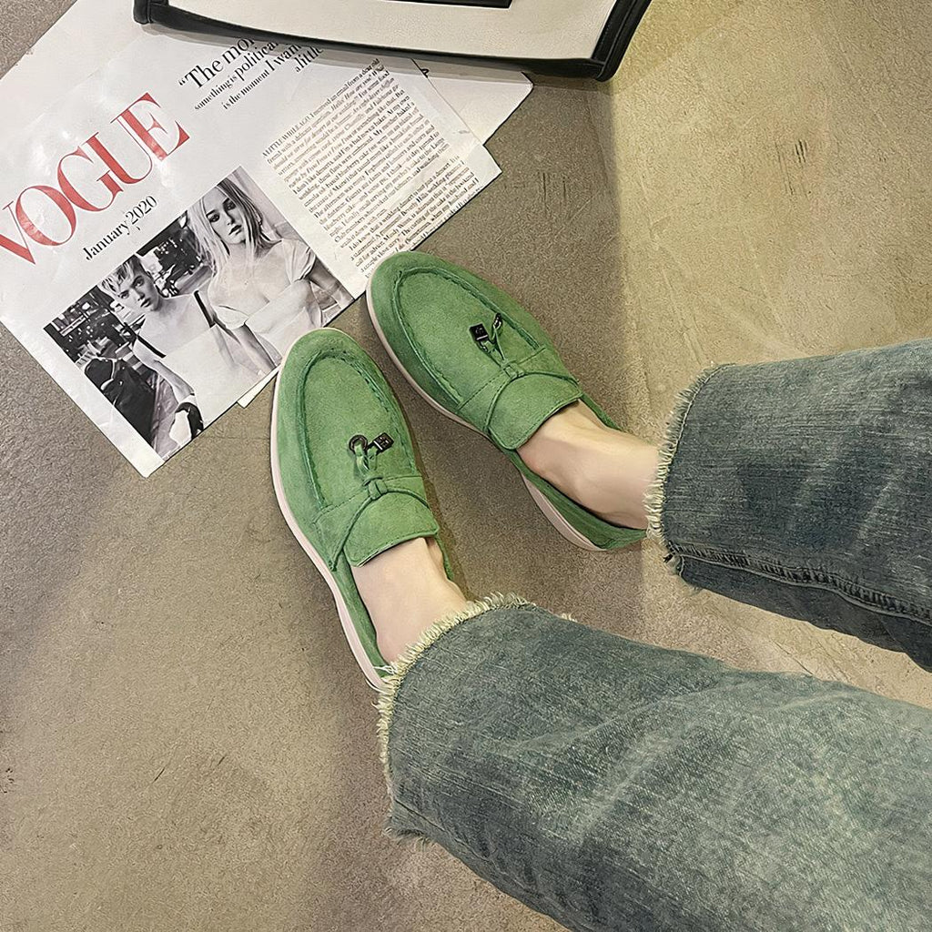 mocassin vert en daim porter par une femme avec un livre devant ses pied