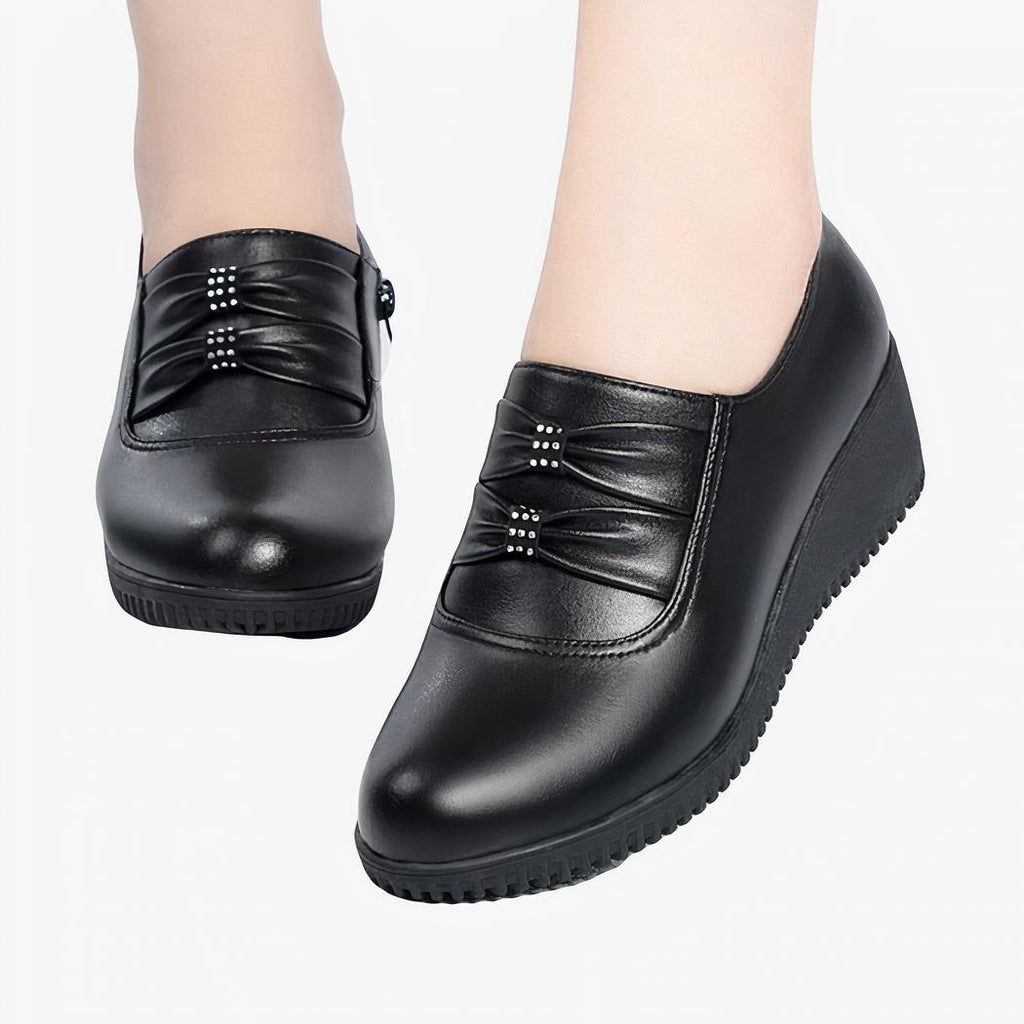 Mocassins compensés confortables effet cuir noir pour femmes avec un fond blanc