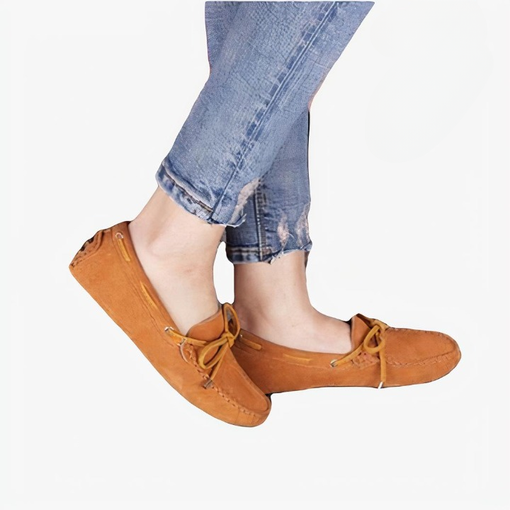 Mocassins marrons portés par une femme dont on voit seulement les mollets.