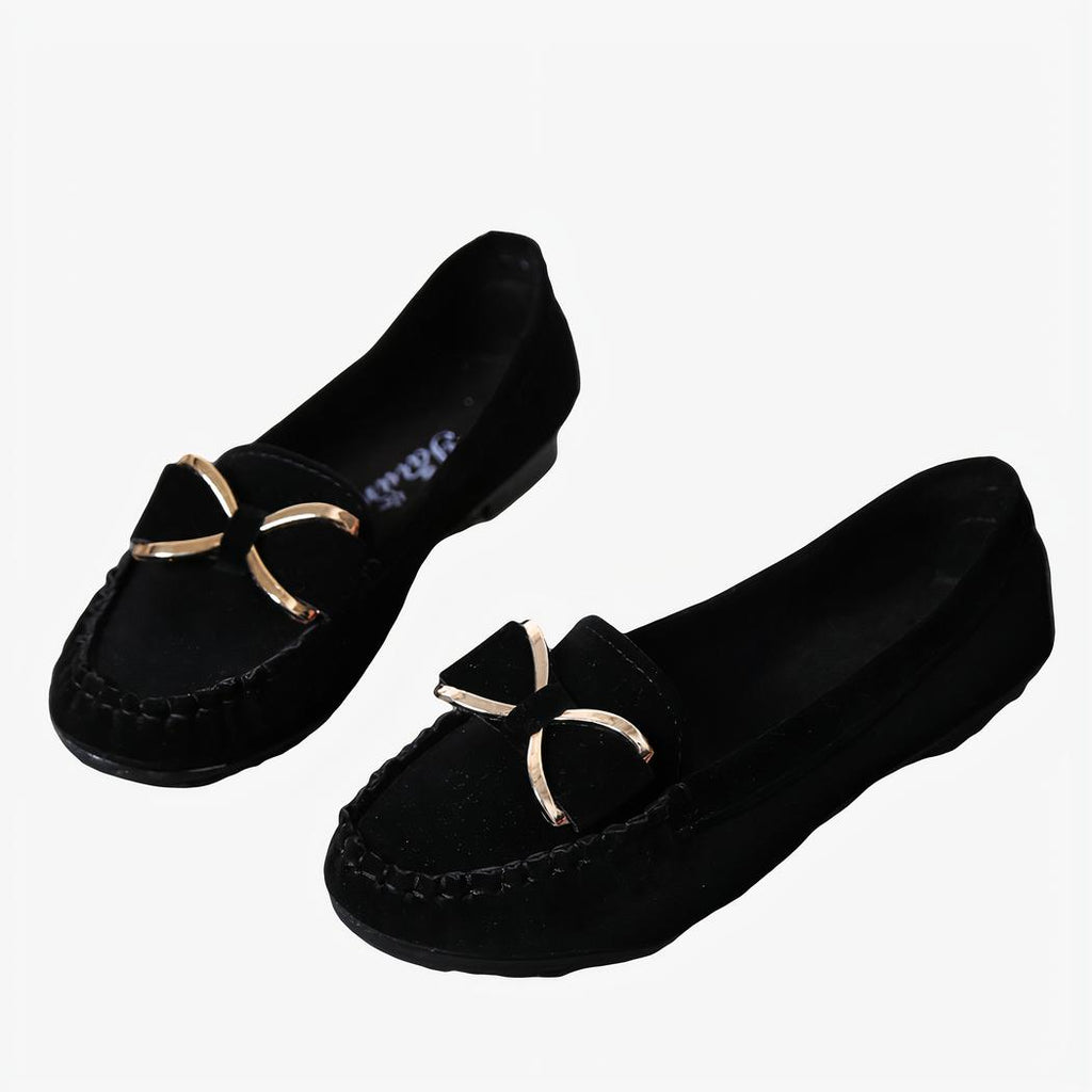 Paire de mocassins noirs avec un nœud doré posés au sol avec des accessoires autour