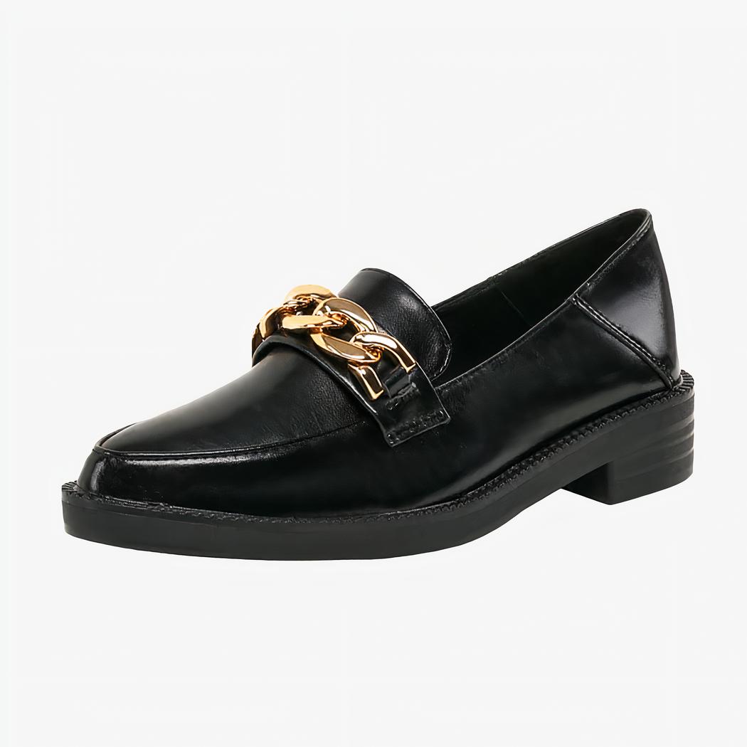 Mocassin en cuir noir verni synthétique avec chaîne dorée décorative sur un fond blanc