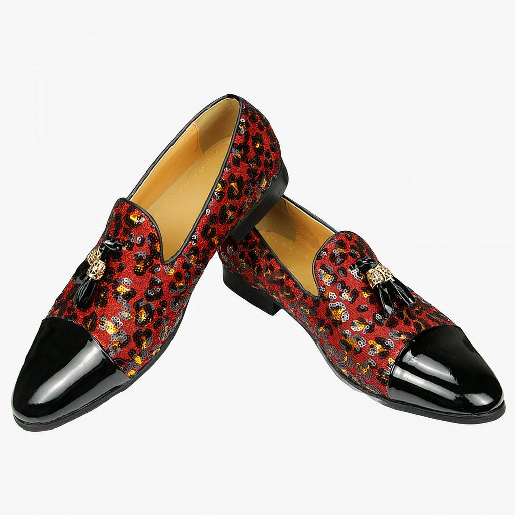 Sur fond blanc, paire de mocassins avec l'avant en vernis noir, le reste du chaussant en sequin motif léopard en rouge avec glands sur le dessus. L'intérieur est beige