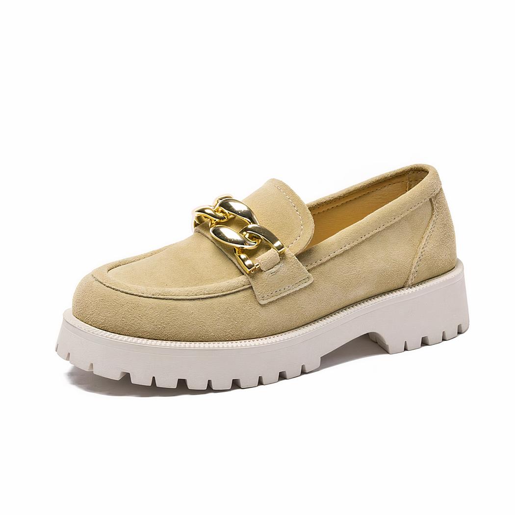 Quatre mocassins en daim de couleurs différentes, gris bleu beige et marron à semelle épaisse et grande boucle dorée décorative alignés sur un fond blanc.