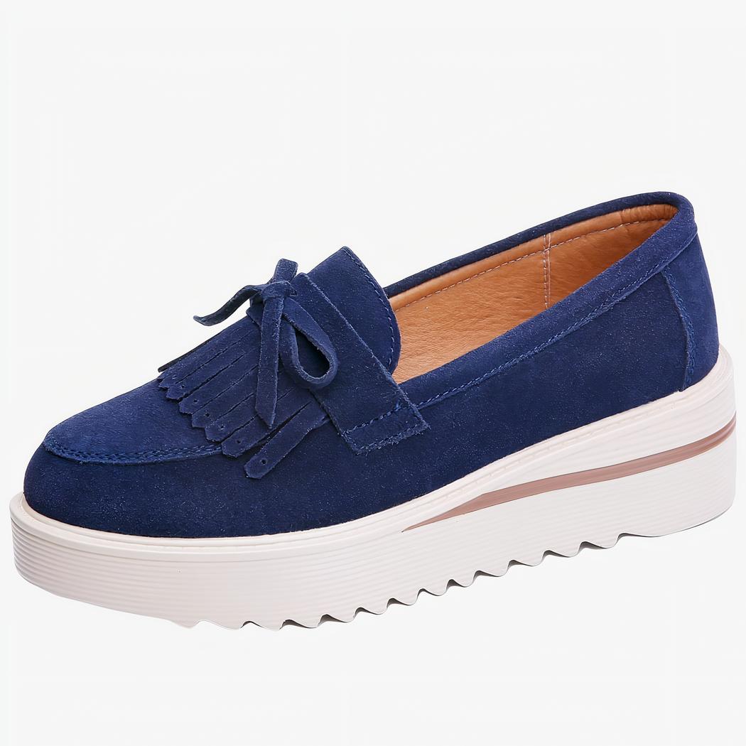 mocassin en daim bleu à gland compensé à semelle blanche sous sur un fond blanc