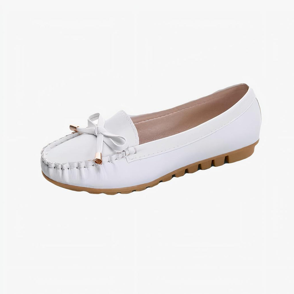 mocassin en faux cuir blanc avec une semelle beige et un gland poser sur un fond blanc