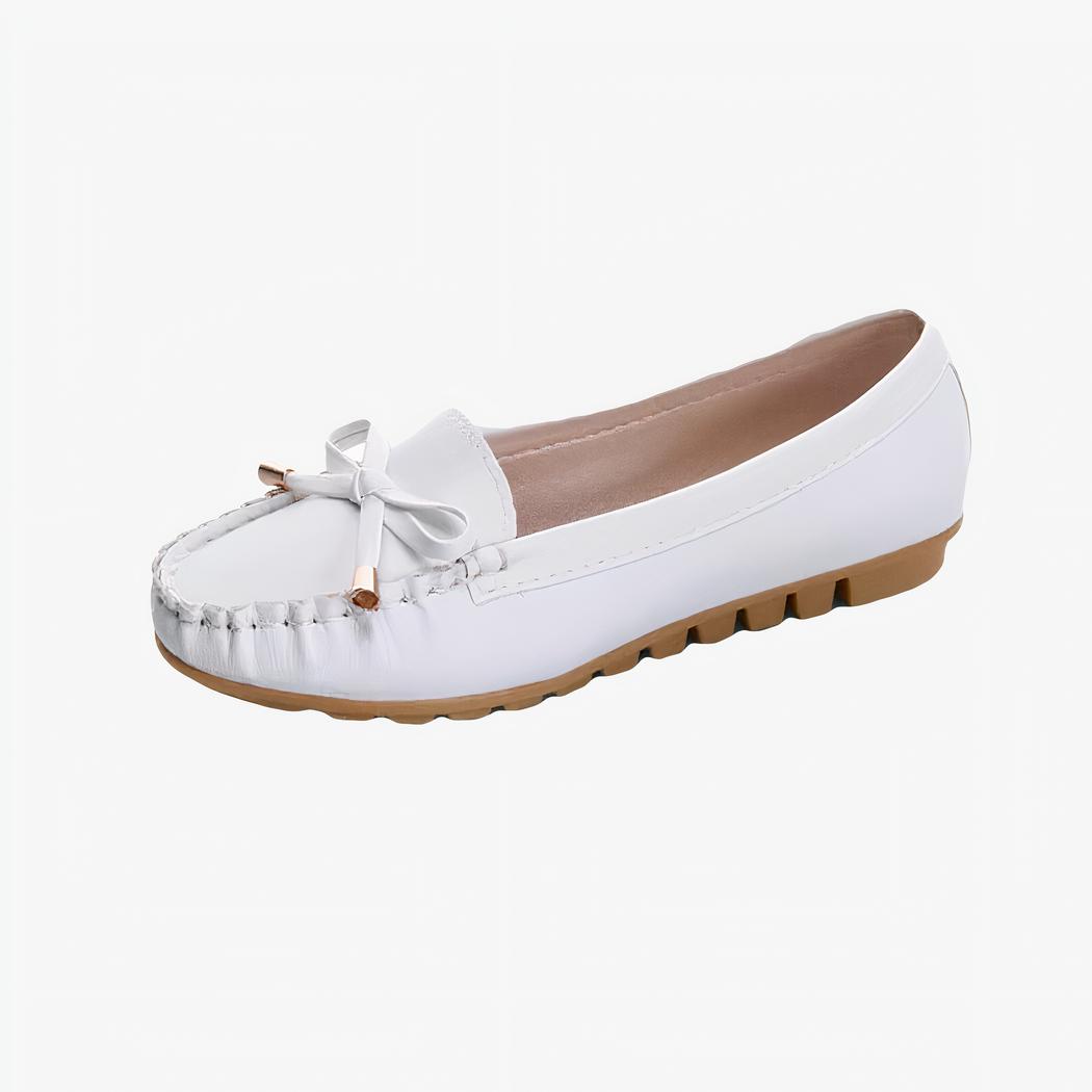 mocassin en faux cuir blanc avec une semelle beige et un gland poser sur un fond blanc