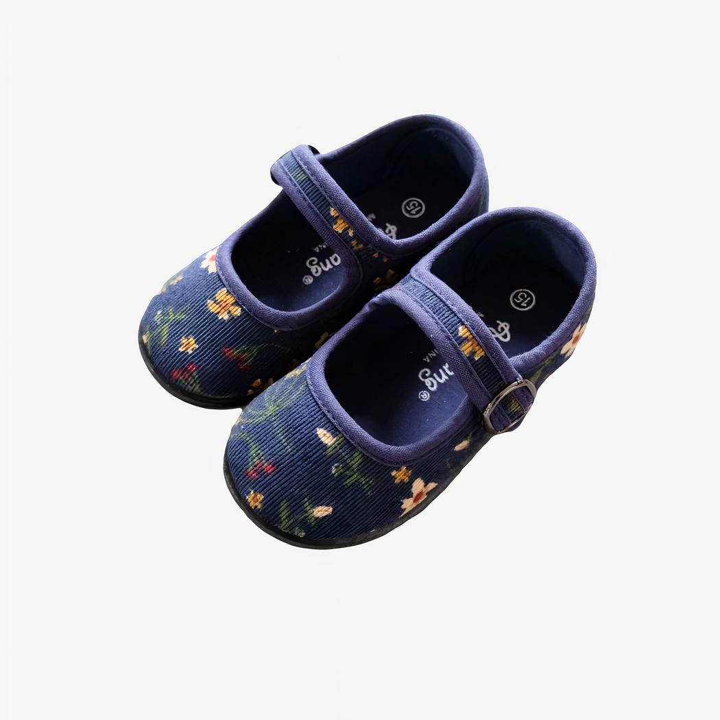 mocassin bleu en velours côtelé pour enfant poser sur un mur gris