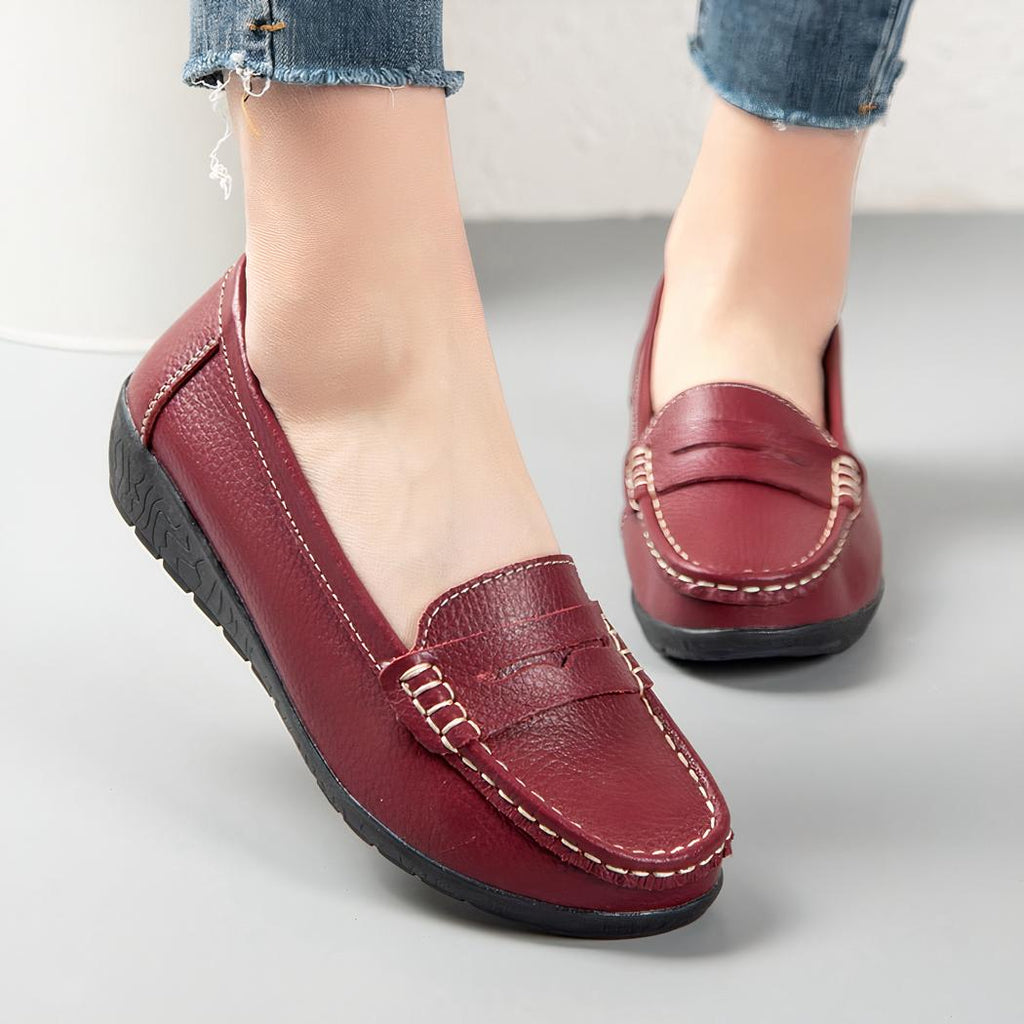 Photo d'une paire de mocassins rouges portée par une femme sur un sol gris