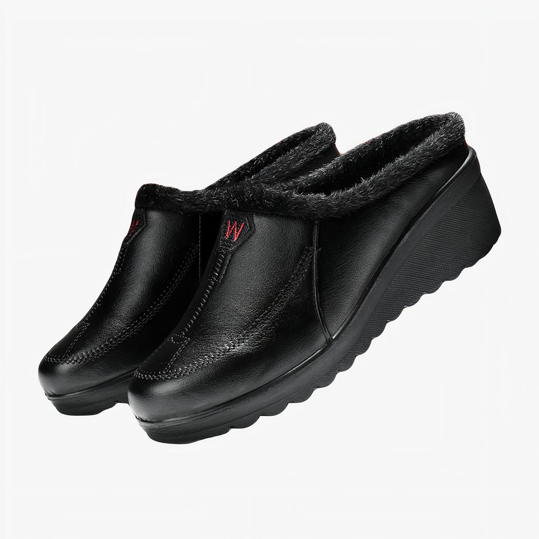 demi mocassin en faux cuir noir poser sur des libres.