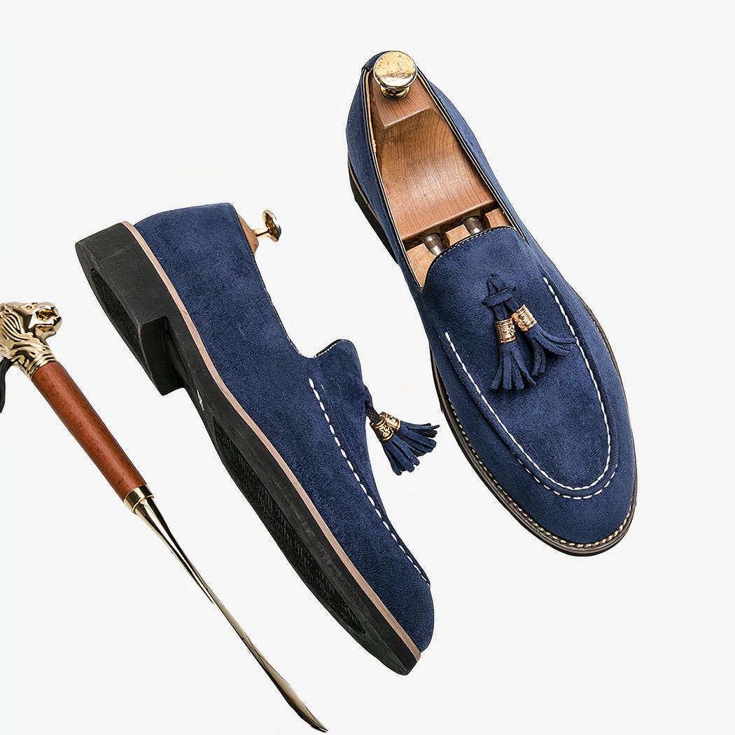 Mocassins bleus avec chausse pied à côté, le tout est posé sur une surface à carreaux blancs.
