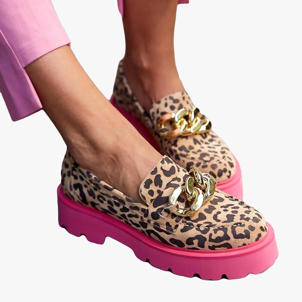 Pied d'une femme portant un pantalon rose et des mocassins léopard à semelles roses