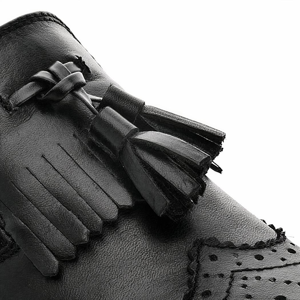 Paire de mocassins noirs à glands sur fond blanc