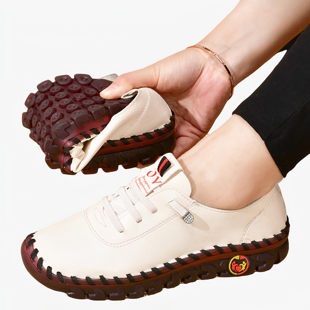 Pied gauche de femme portant un mocassin orthopédique blanc, avec la deuxième chaussure pliée dans la main droite